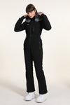 Combinaison de ski une pièce pour femme avec capuche en fourrure, style hiver chic.